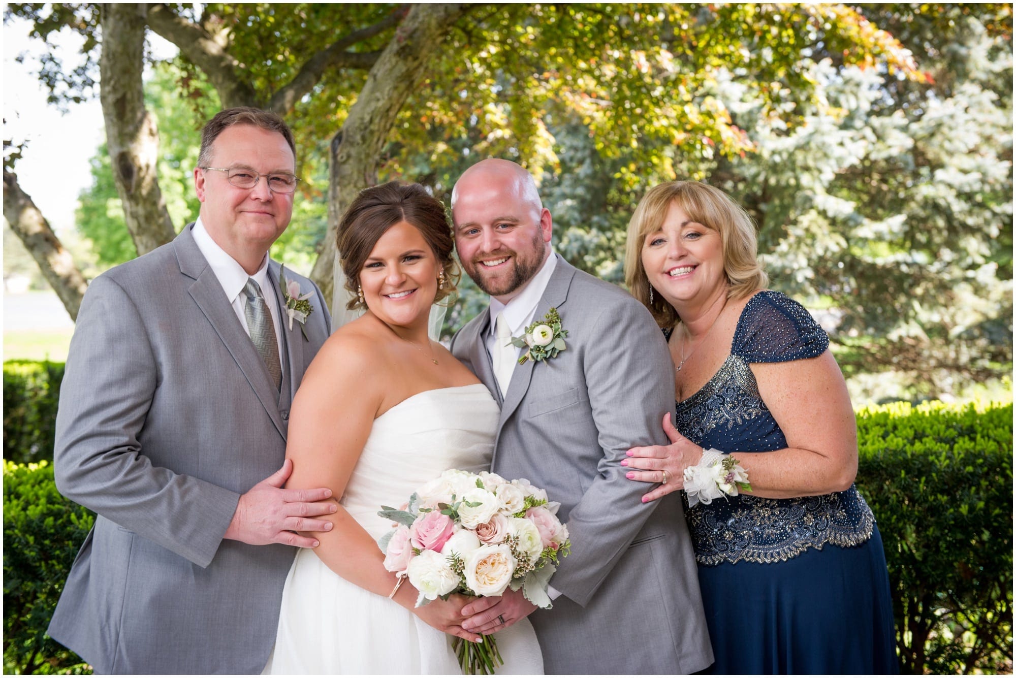 bride and groom foral portraits outside of church with parents of groom 