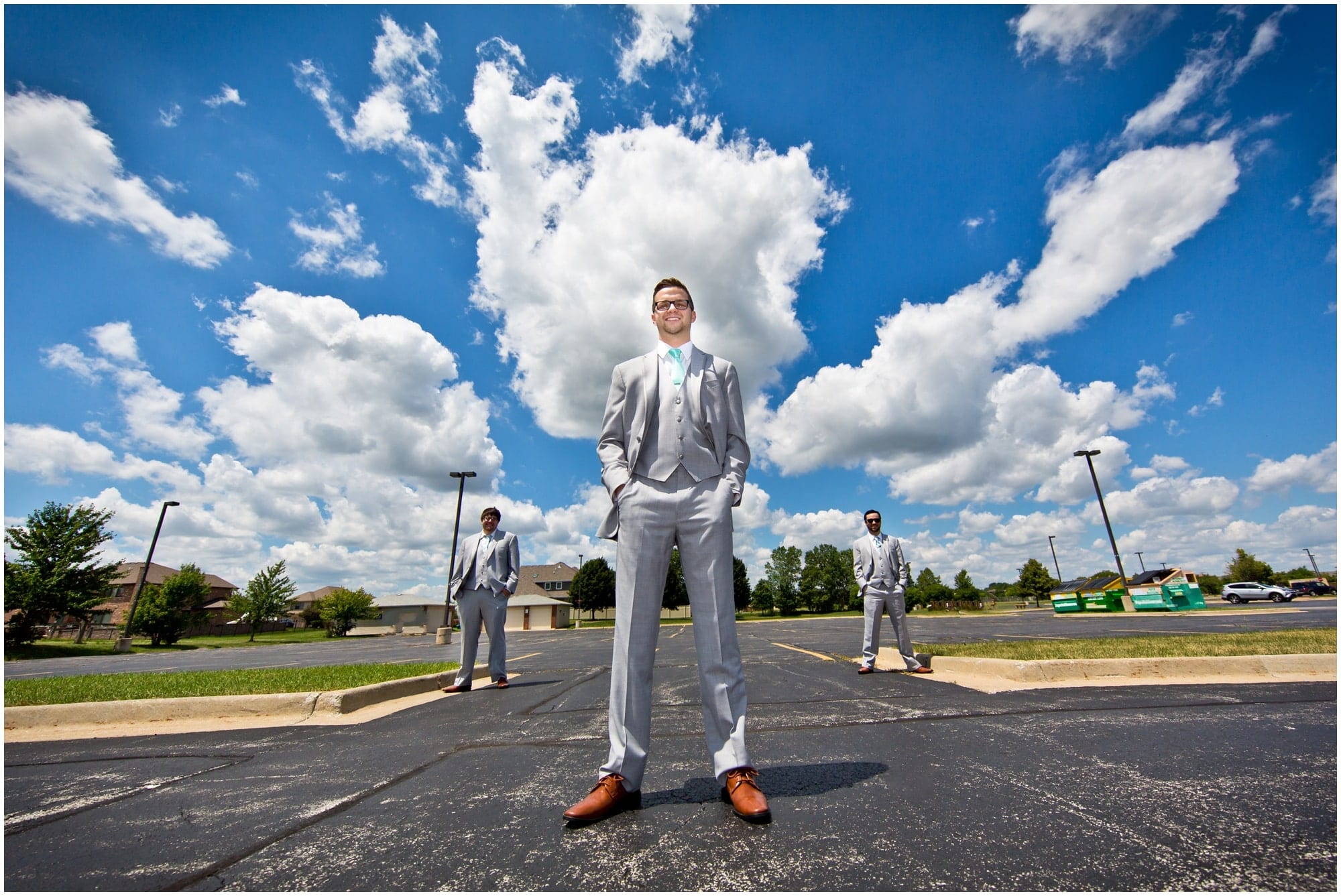County Line Orchard Wedding Photographer artistic wide angel portrait of groom with 2 groomsmen and big white clouds and bright blue sky