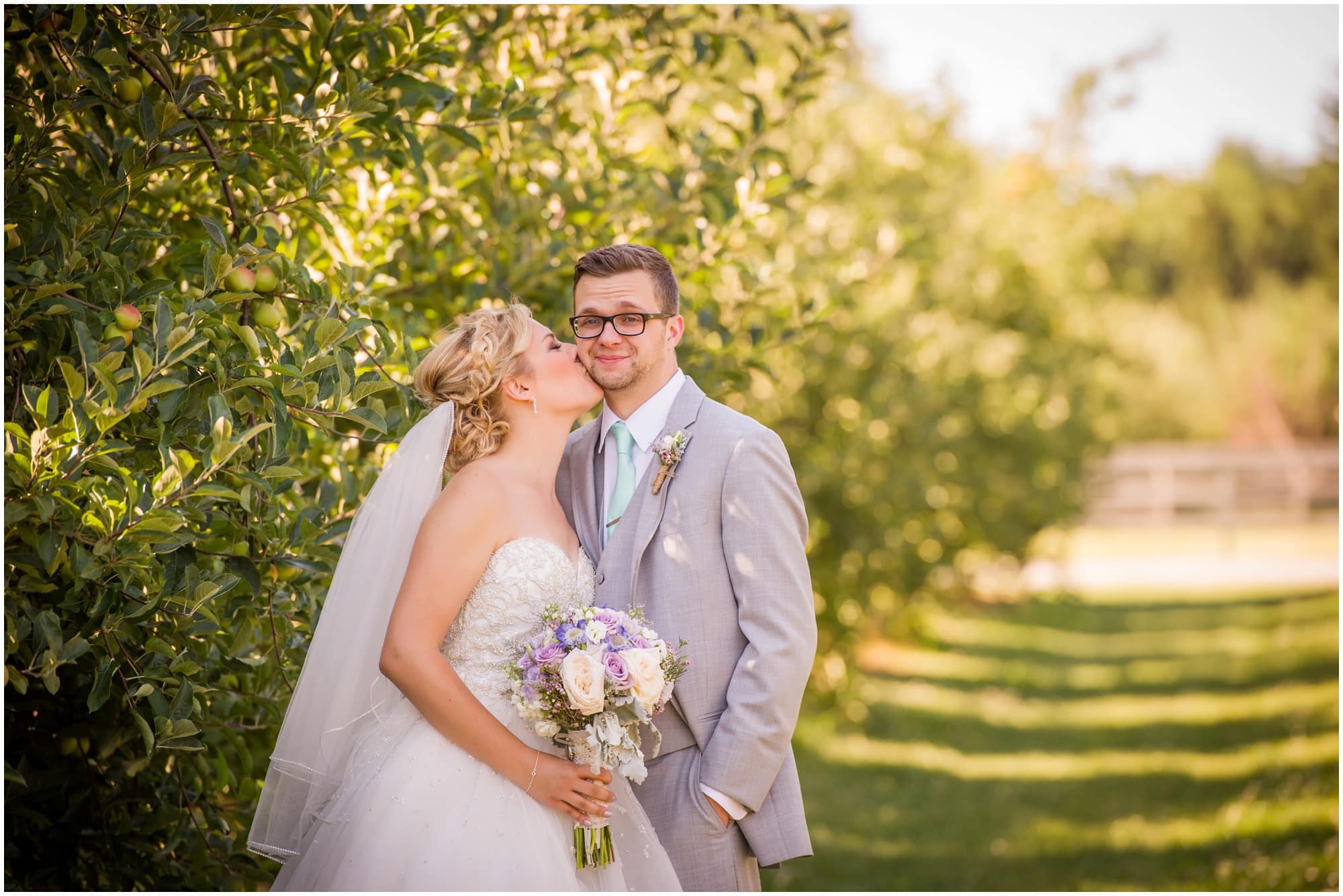 County Line Orchard Wedding Photographer bride kissing groom on cheek in orchard 