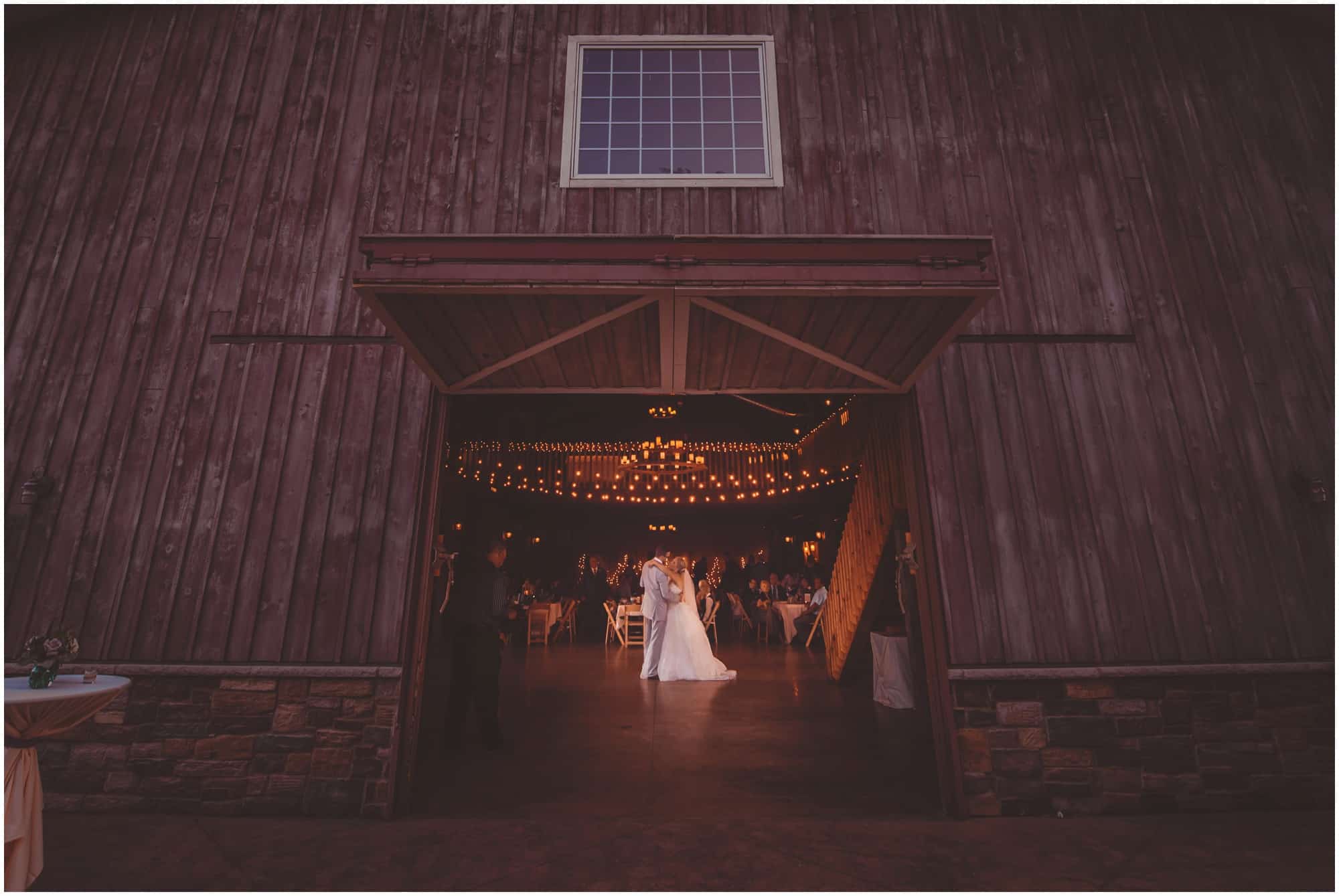County Line Orchard Wedding Photographer bride and groom dancing together photographed from outside the barn doors, with the barn doors framing the couple dancing 